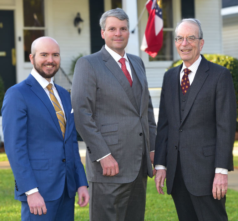 Tanner Lowe, John Moorhead, and Bill Moorhead stand outside their firm offices.